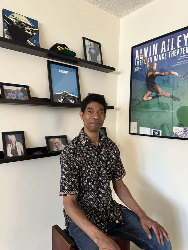 Craig Dunham, Rolf Method of Structural Integration practitioner in Los Angeles, seated in his Santa Monica office with photos of Dr. Ida Rolf and his teachers — Emmett Hutchins, and Neal Powers — behind him.