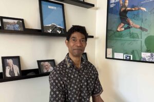 Craig Dunham, Rolf Method of Structural Integration practitioner in Los Angeles, seated in his Santa Monica office with photos of Dr. Ida Rolf and his teachers — Emmett Hutchins, and Neal Powers — behind him.