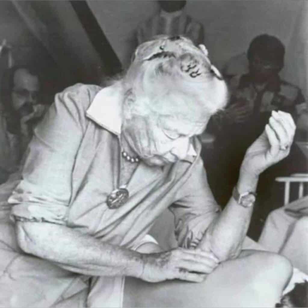 Black and white photo of Dr. Ida Rolf working on a client during a Structural Integration session, with her students observing in the background.