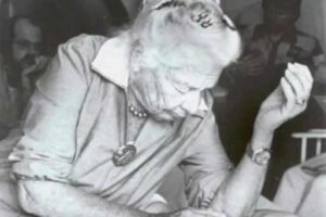 Black and white photo of Dr. Ida Rolf working on a client during a Structural Integration session, with her students observing in the background.