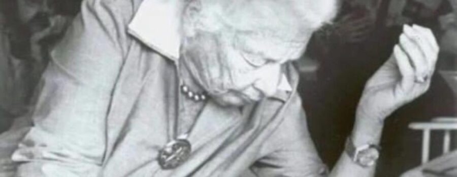 Black and white photo of Dr. Ida Rolf working on a client during a Structural Integration session, with her students observing in the background.