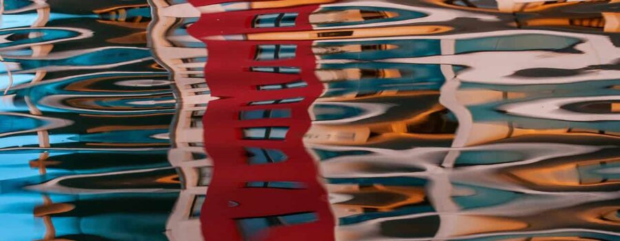 Buildings reflected in water — a visual metaphor for the question: Rolfing or massage, which is the right choice for you?