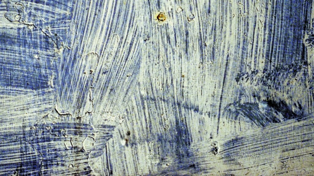 Abstract textured surface with blue and white brush strokes in layered patterns.