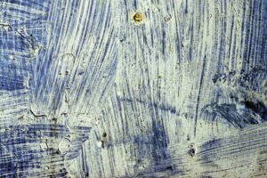 Abstract textured surface with blue and white brush strokes in layered patterns.
