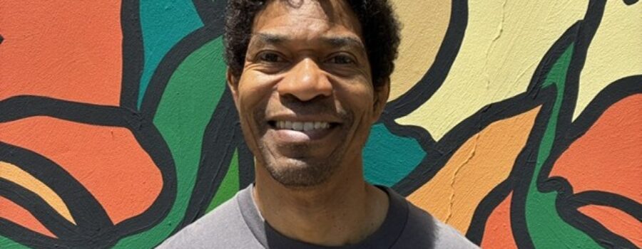 Craig Dunham, Advanced Rolf Method practitioner, standing in front of a colorful mural outside his Santa Monica office building.